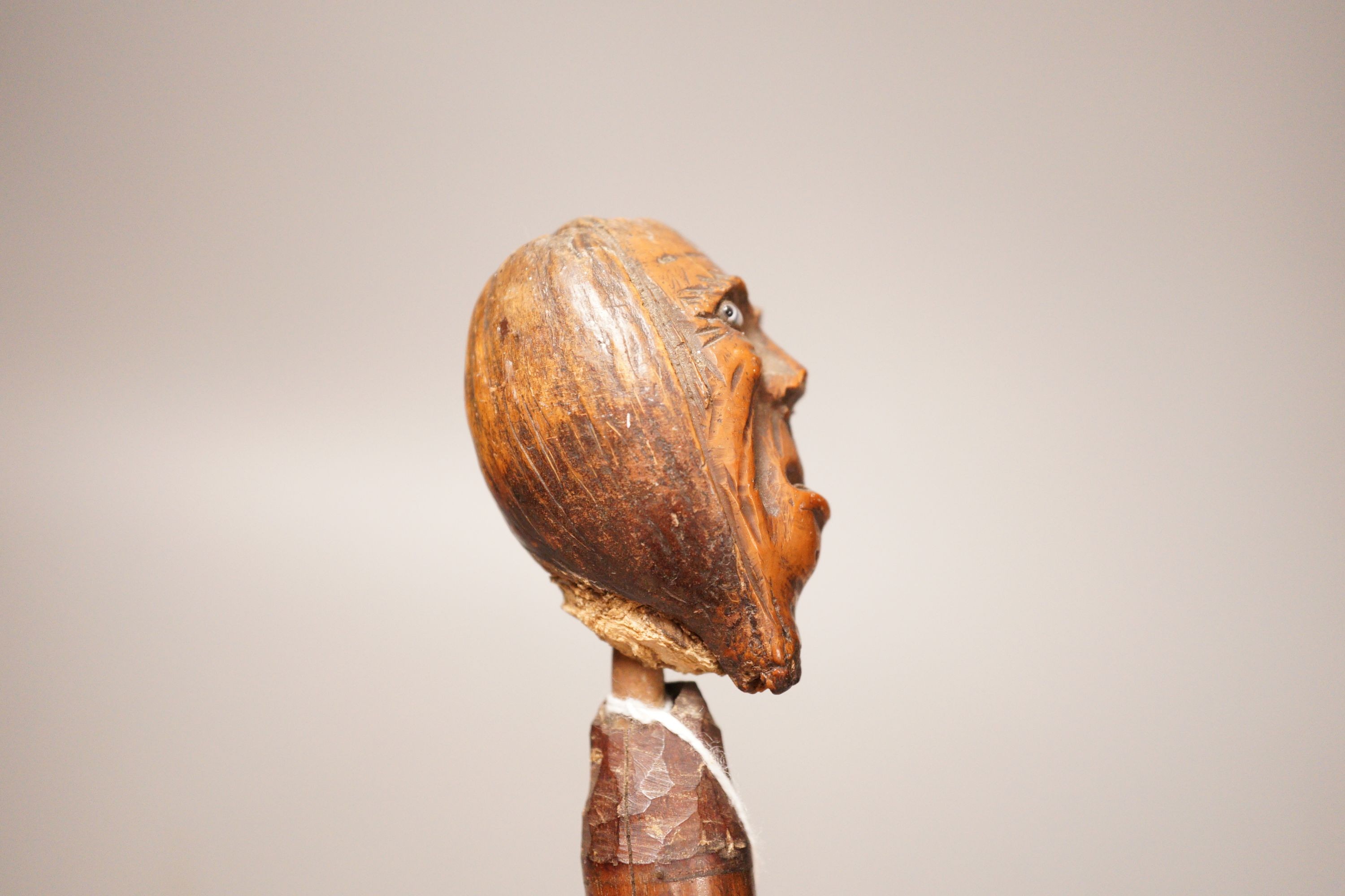 A 19th century continental carved head with glass eyes on associated cane stick. Total length 92cm